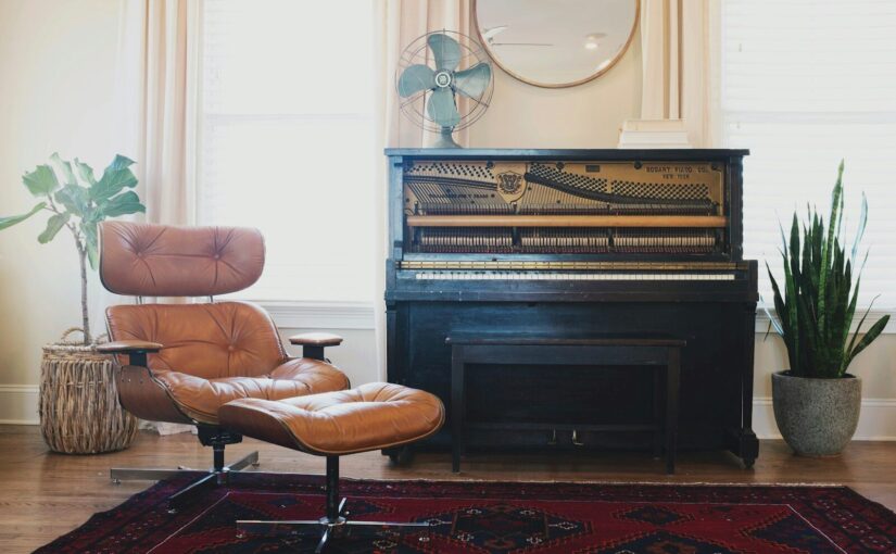 black upright piano near brown leather padded chair